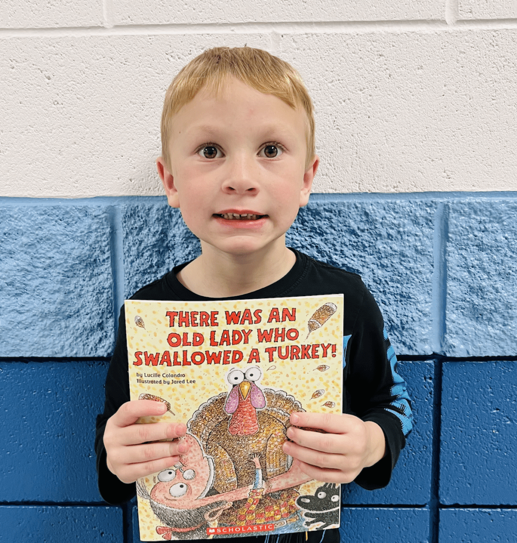 student holding a book received for earning a  praise award